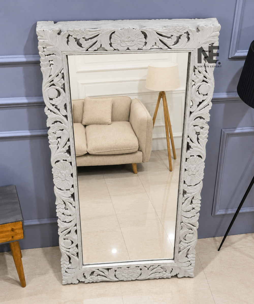 2. Top-angle view of a white wooden full-length mirror featuring intricate floral carvings in a paneled living room.