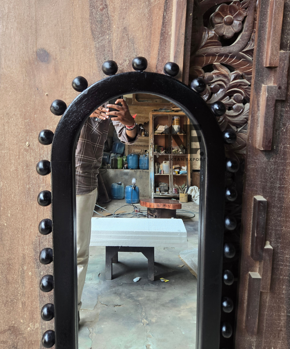 Close-up of rounded black studs on an arched mirror frame