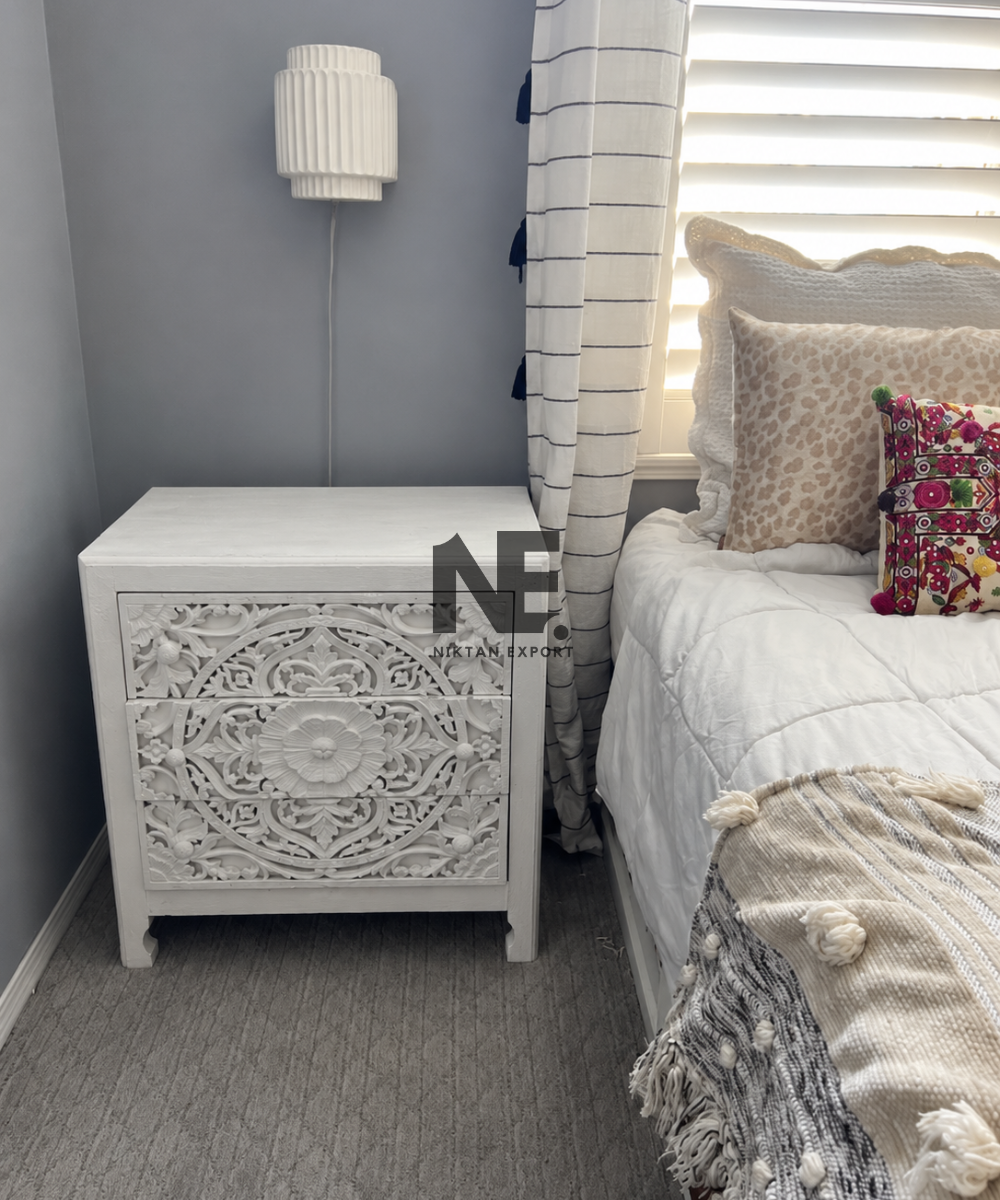 White carved wooden bedside table with three drawers